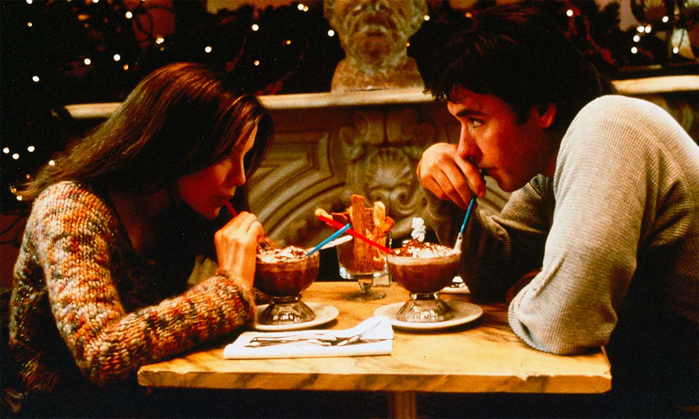 Still from the movie Serendipity, John Cusack and Kate Beckinsale seated at a table having a dessert.