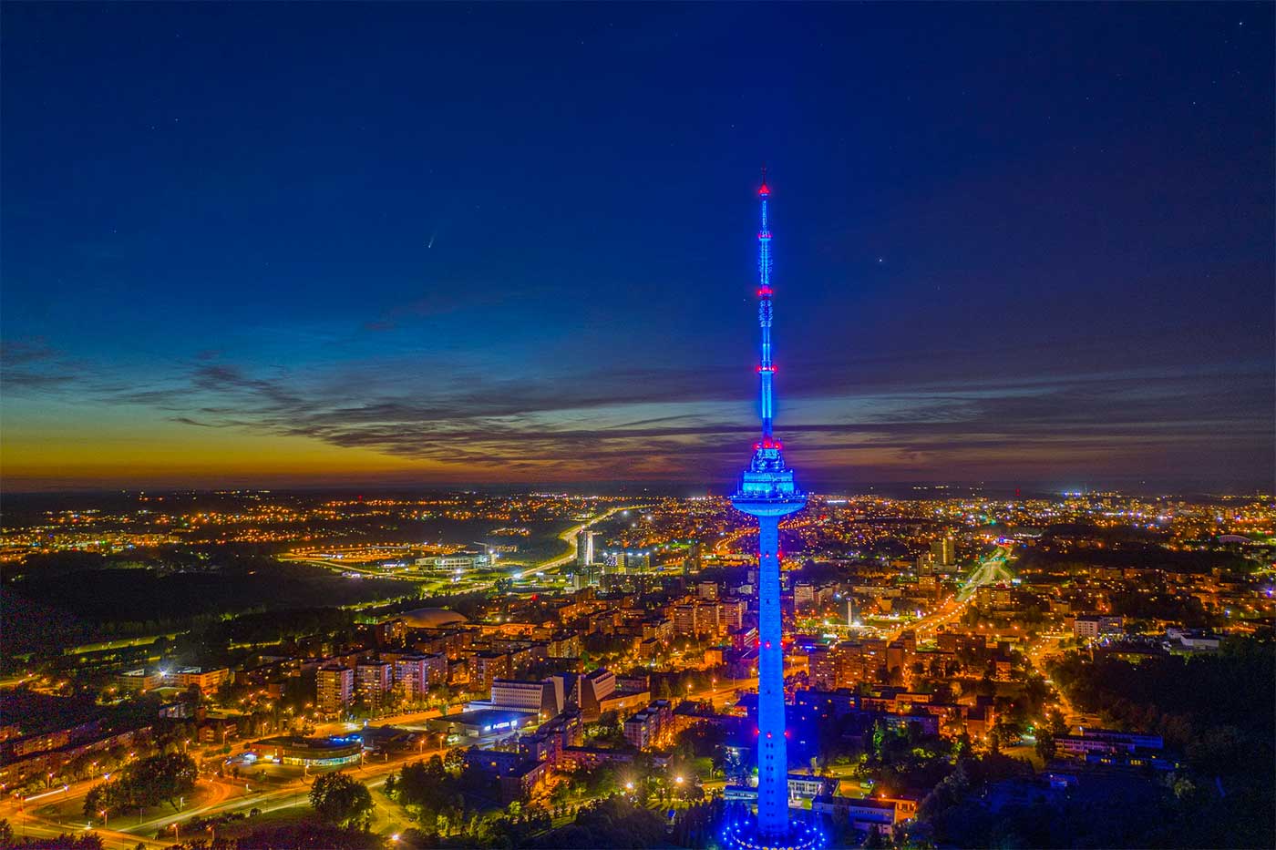 TV tower at night with lit up city.