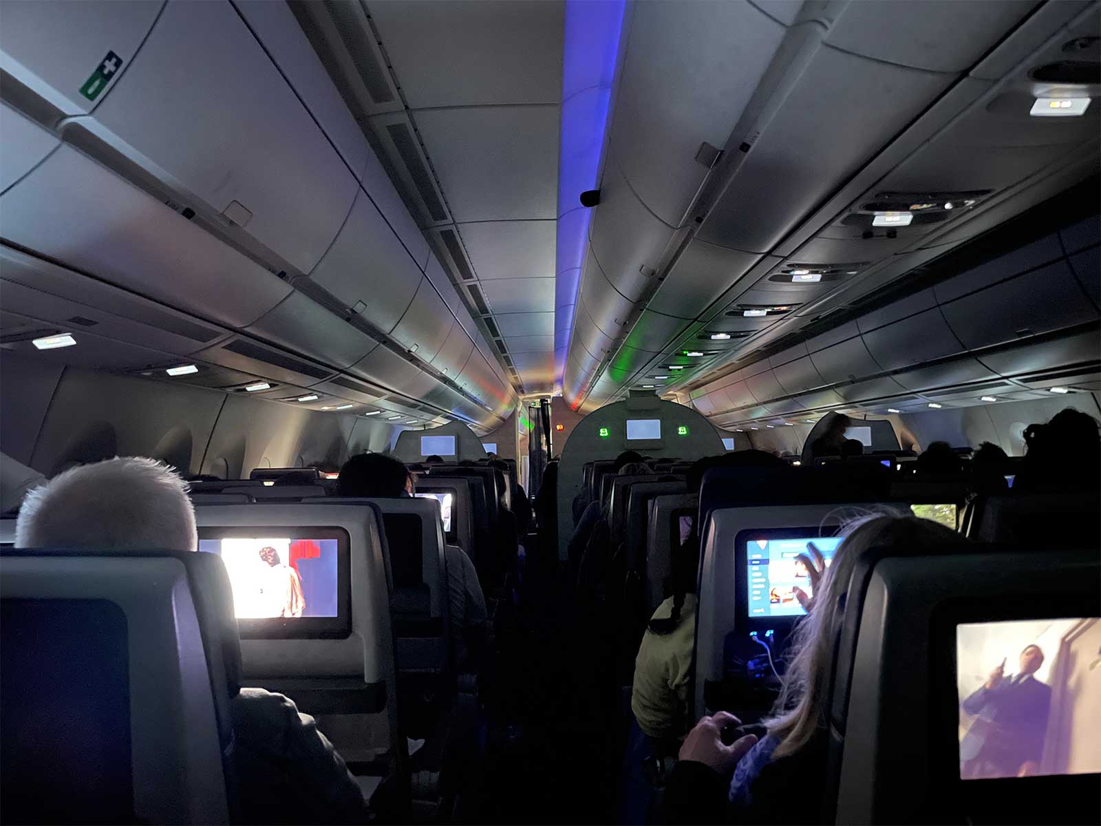 Economy class aisle seen from back of aircraft during overnight flight.