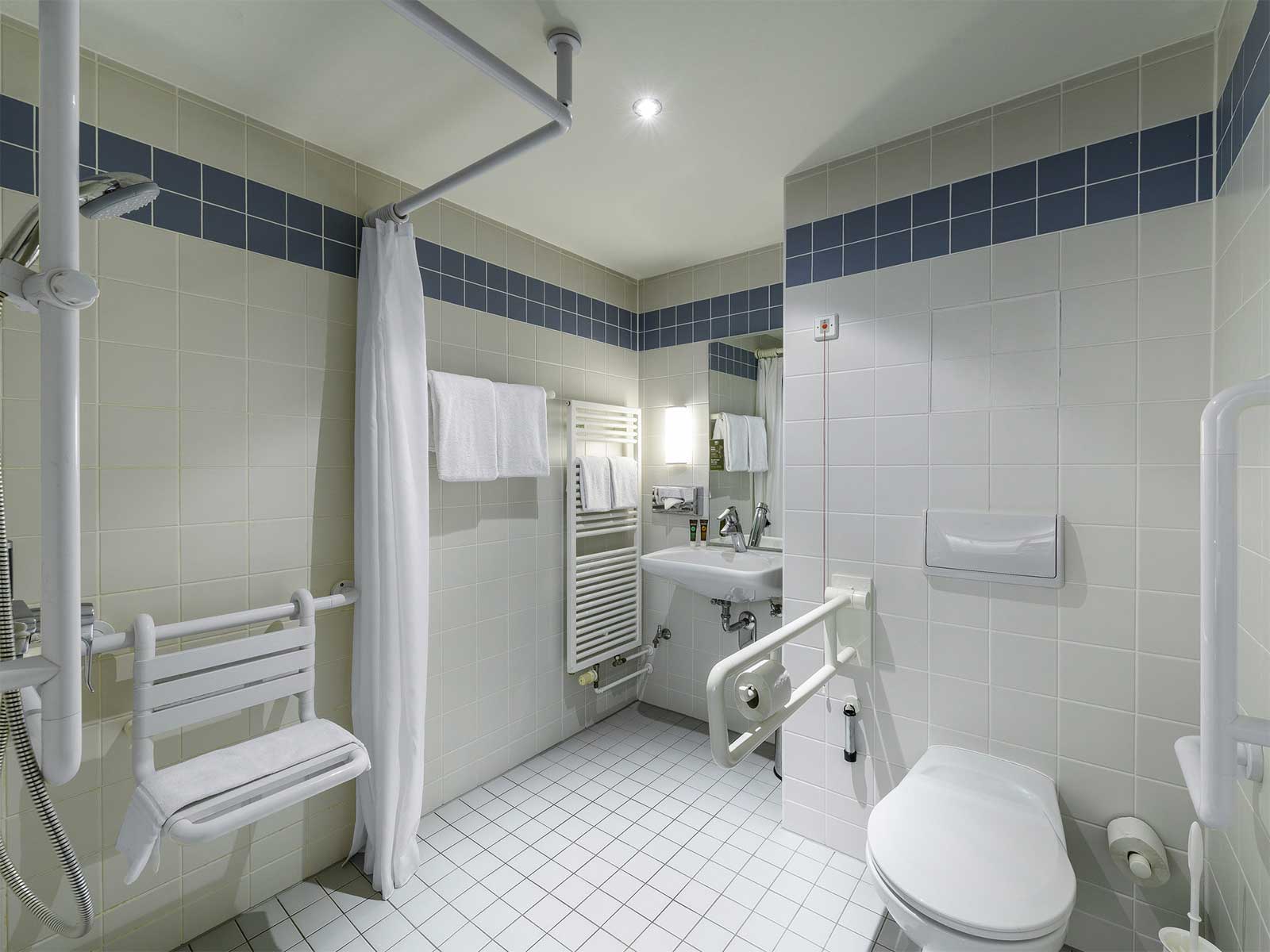 Accessible bathroom with roll under sink, roll in shower and toilet with grab bars.