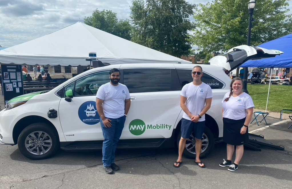 Autonomous van with wheelchair ramp deployed from rear of vehicle.