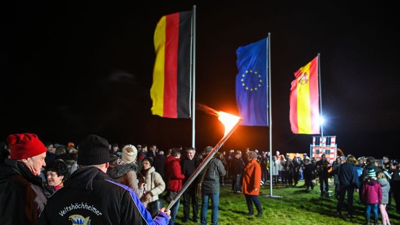 People gathered around the European Union flag at night in a field.