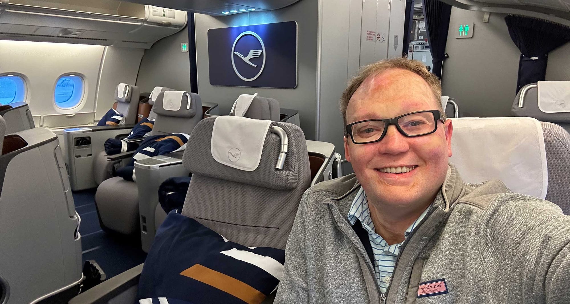 John seated in business class on a Lufthansa Airbus A380 aircraft.