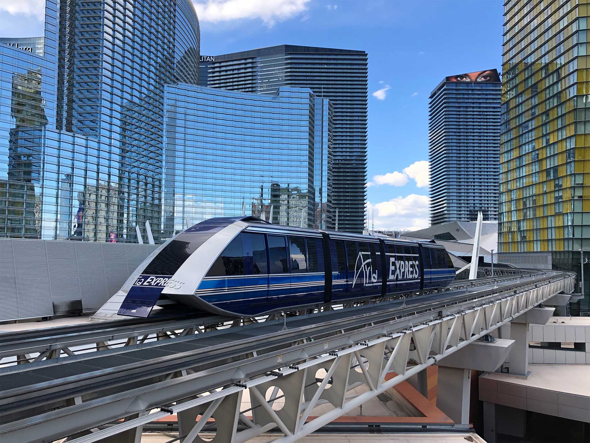 Tram approaching station in front of hotel towers.