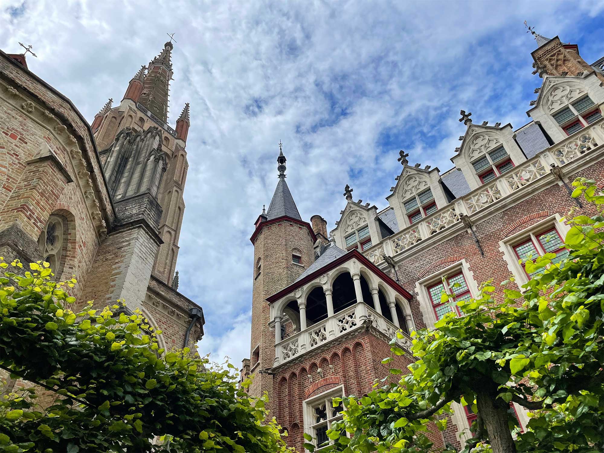 Exterior of church seen from courtyard lined with green trees.