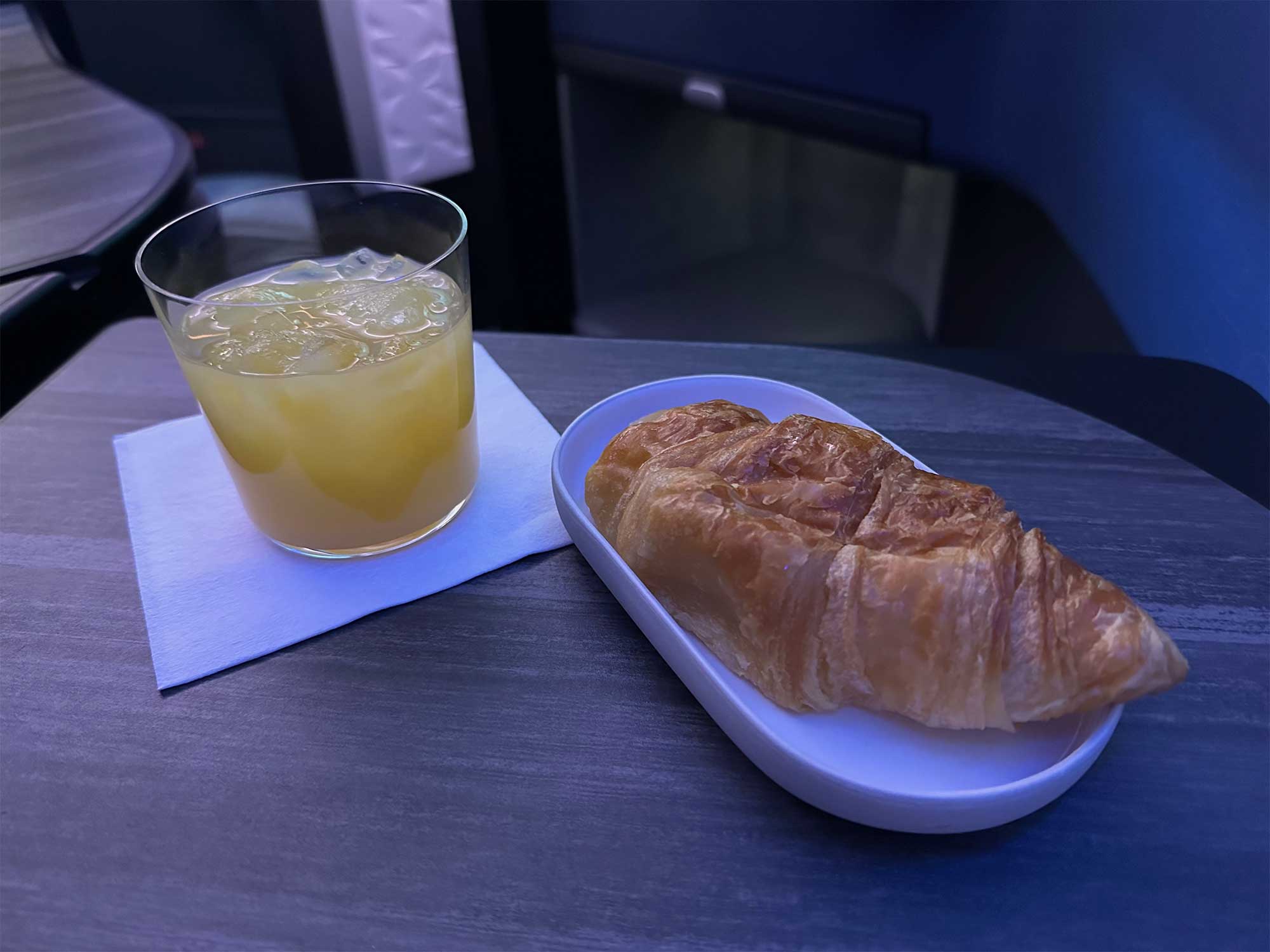 Glass of orange juice and croissant.