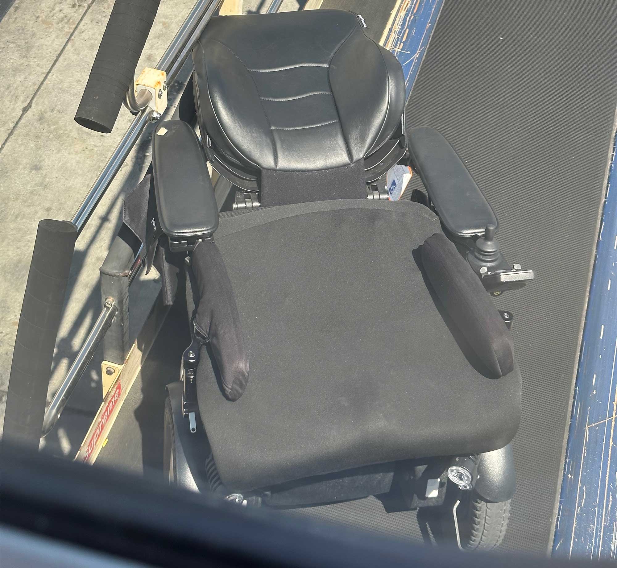 Wheelchair positioned at an angle relative to the baggage belt on a loading device.