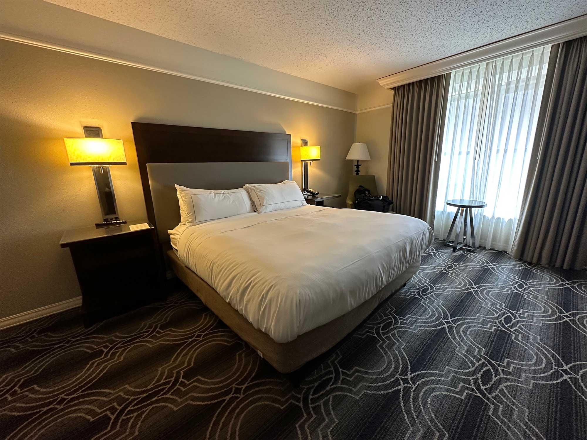 King size bed in carpeted hotel room.