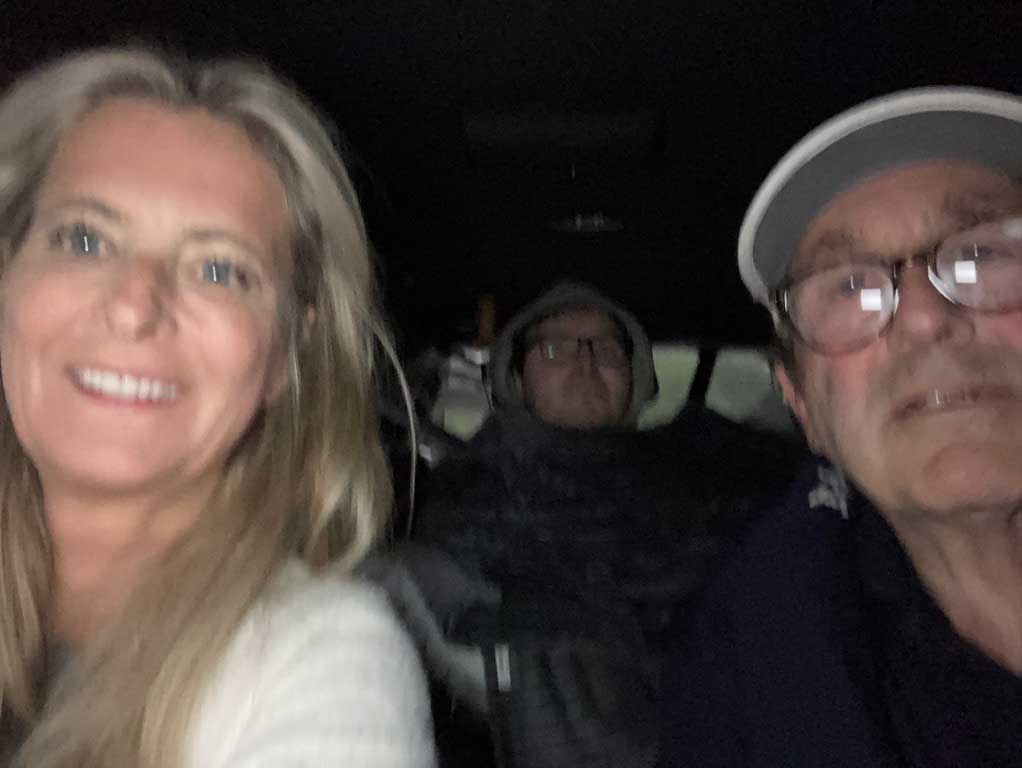 Selfie taken in van with Alan's parents in the foreground and he in the background in the early morning pre dawn light.