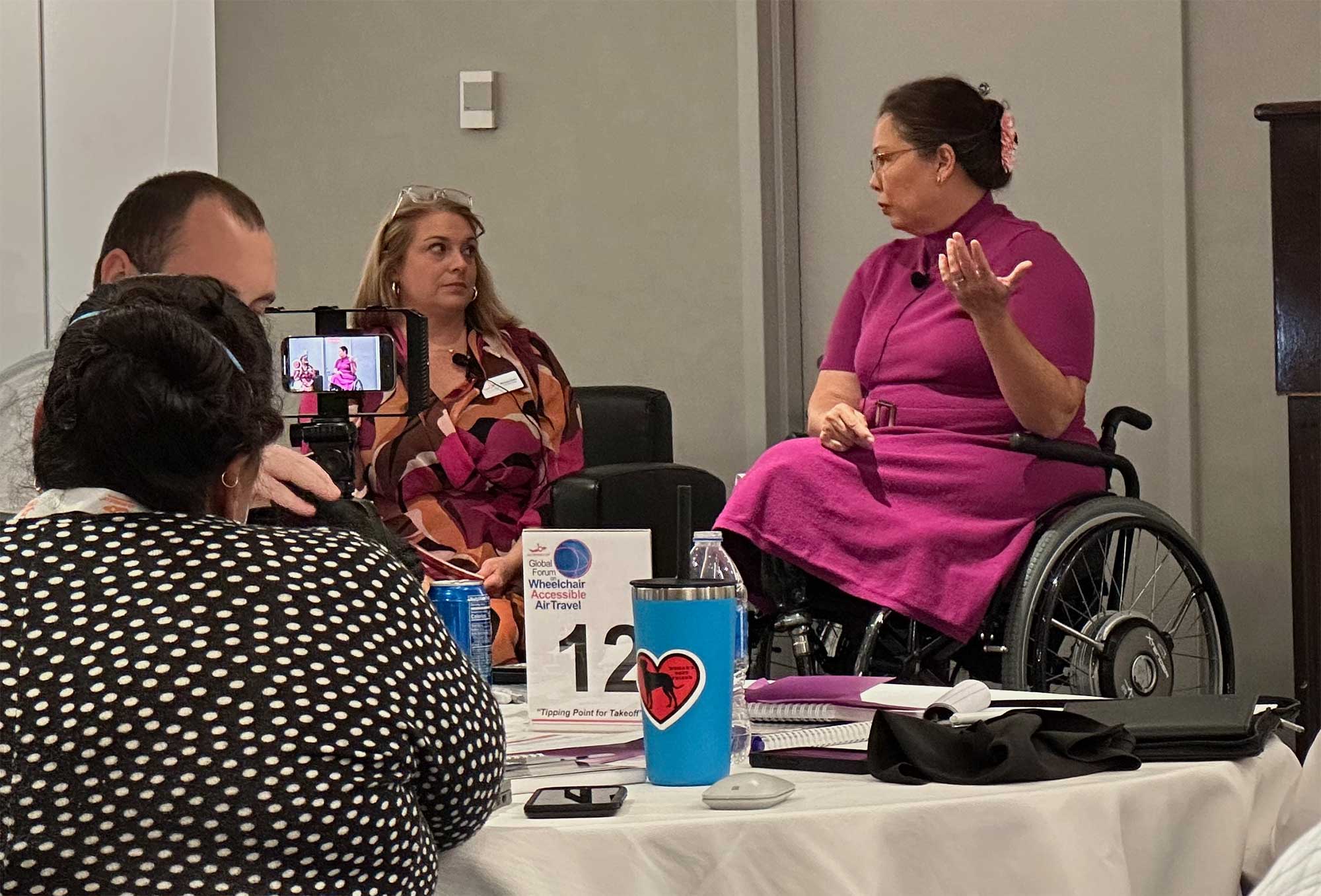 Senator Tammy Duckworth wearing a pink dress on stage next to Michele Erwin.