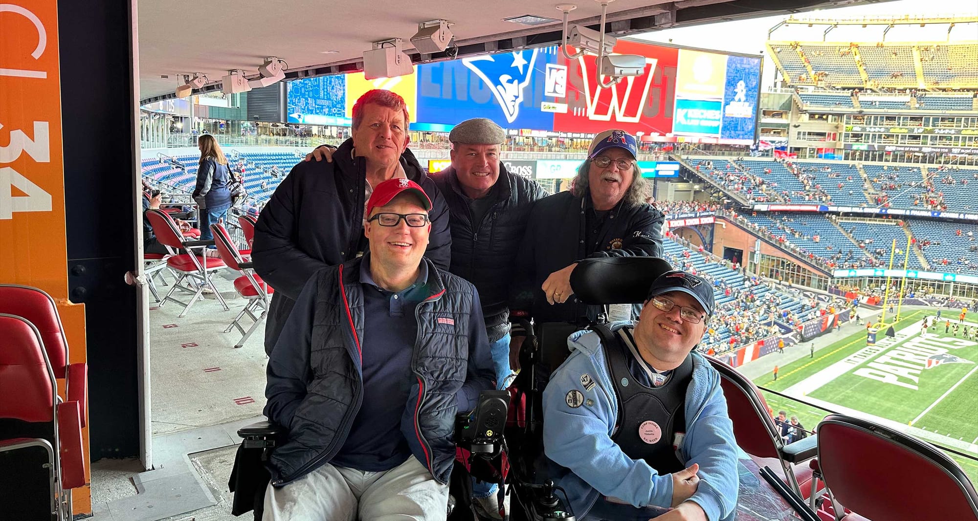 John with four new friends at the football game, one of whom is also a wheelchair user.