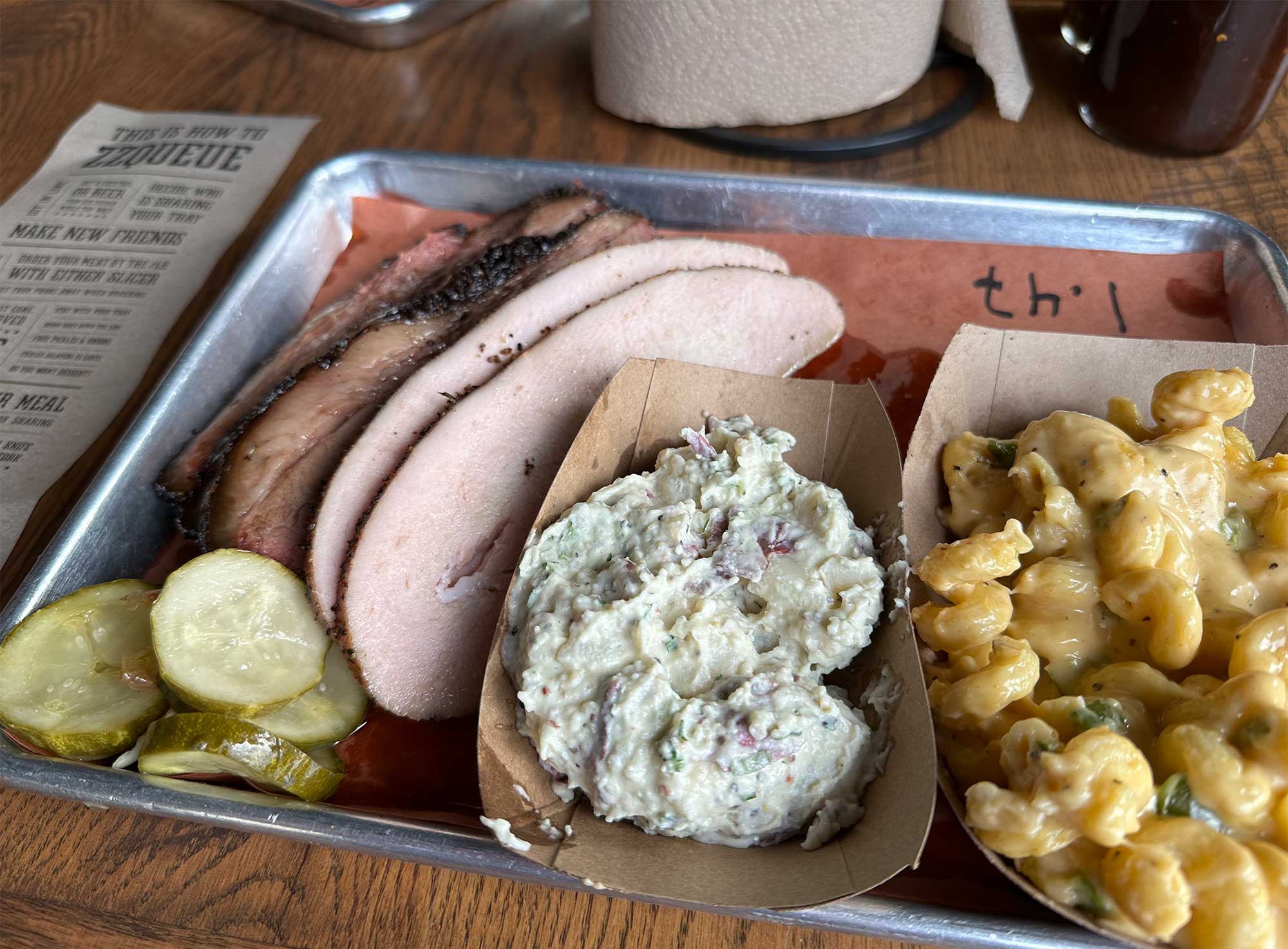 Barbecue tray with brisket, turkey, macaroni and cheese, and potato salad.