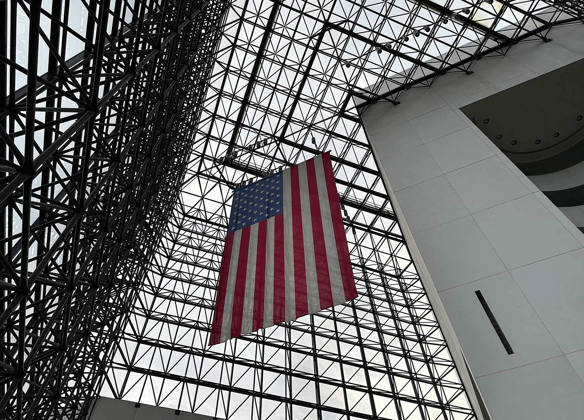 American flag hanging from the ceiling inside a large glass atrium.