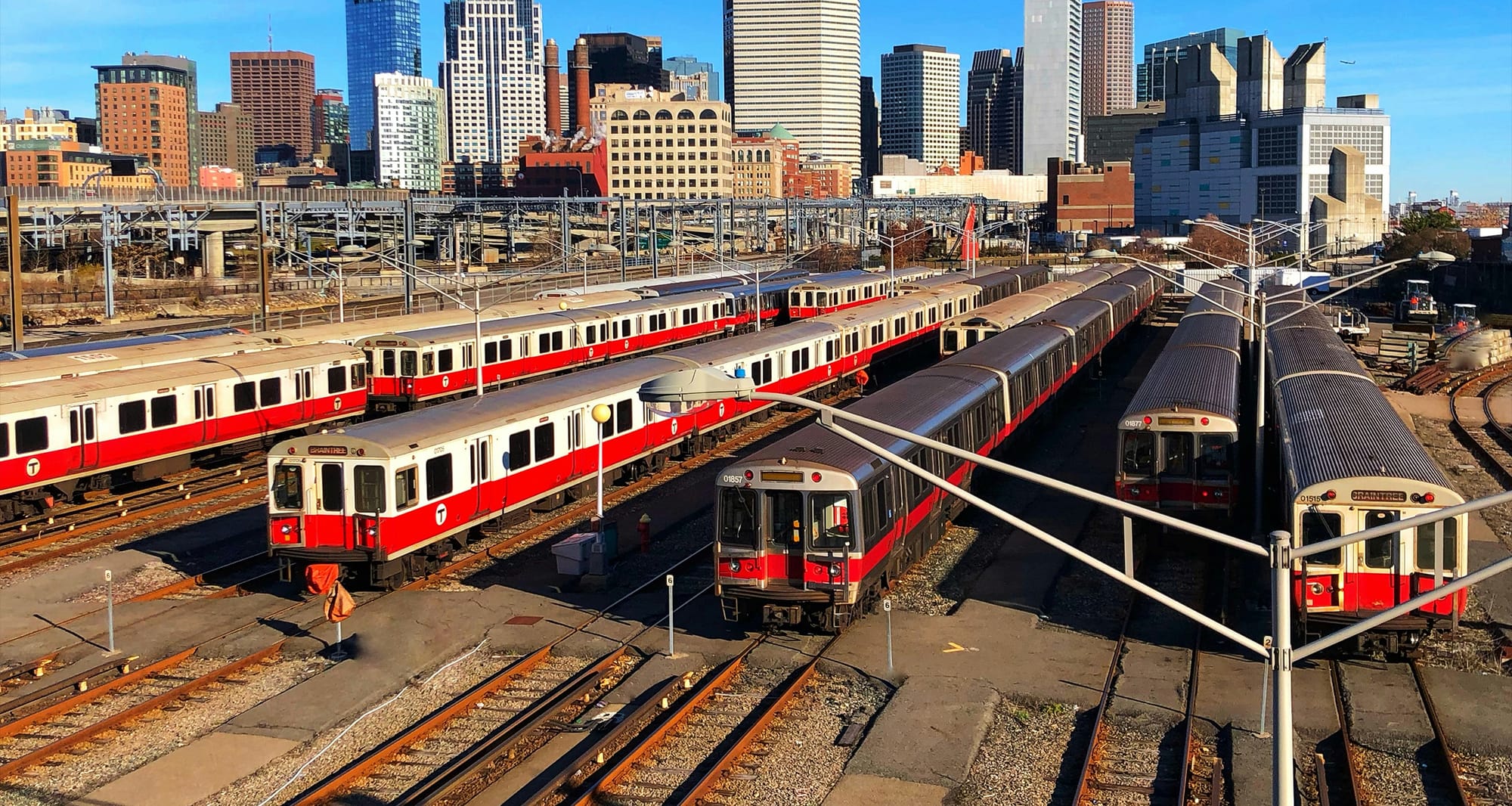 Subway trains parked at depot with city skyline in the background.