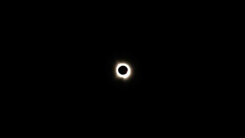 View of the moon in front of the sun against a black background.