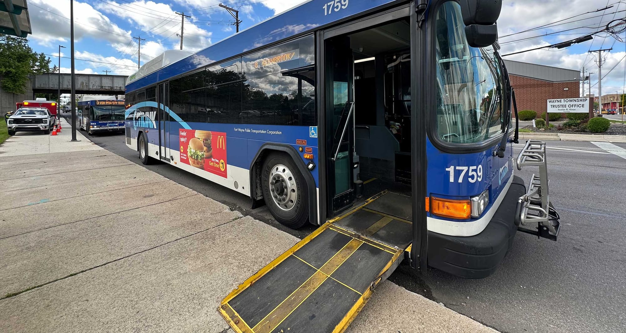 City bus with wheelchair ramp deployed on sidewalk.